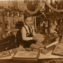 A vintage photo of a ittle boy sitting under the christmas tree